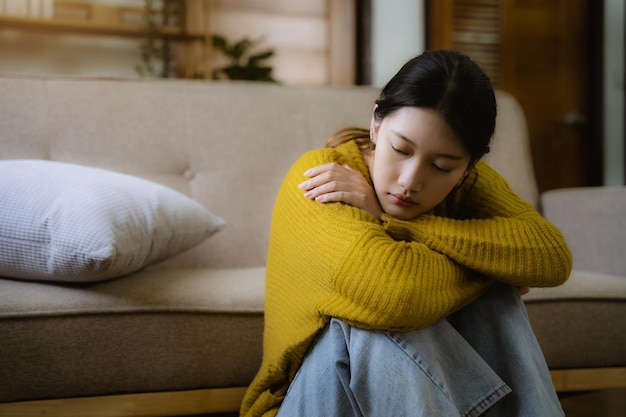 Sad and depressed young asian female sitting on the floor in\
the room sad mood feel tired lonely and unhappy concept selective\
focus