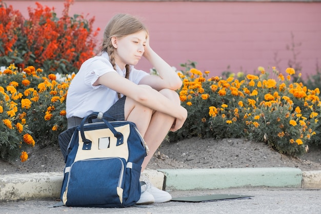 いじめや嫌がらせに苦しんでいる悲しい絶望的な少女は、孤独に倒れ、不幸な絶望的で絶望的な屋外に座っています。学校の孤立、虐待、いじめの概念