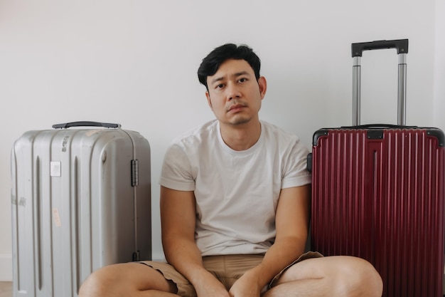 Photo sad disappointed man sit with his luggages as his traveling trip plan has been cancelled