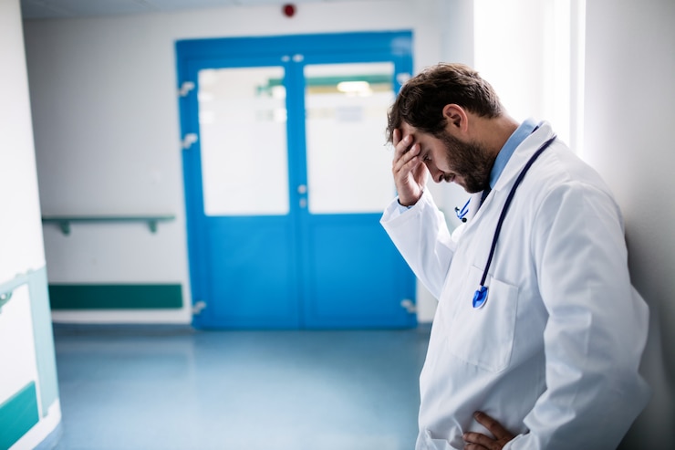 Photo sad doctor leaning against the wall