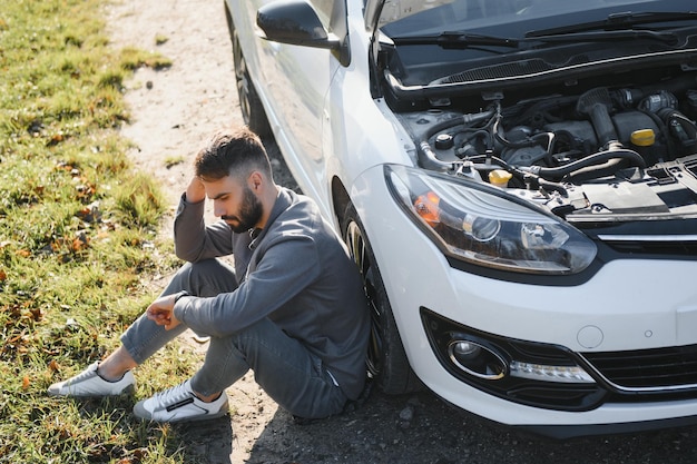 Photo sad driver holding his head having engine problem standing near broken car on the road car breakdown concept