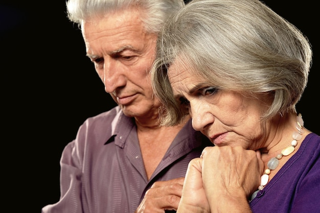 Sad elderly couple on a black background