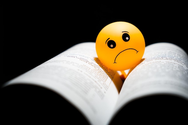 Photo sad emoji on the book with black background