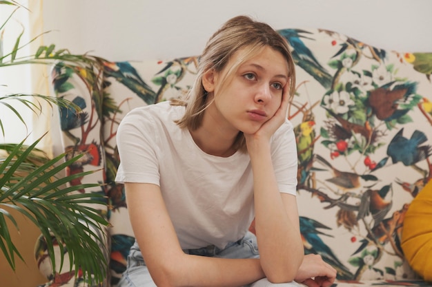 Photo sad emotion young woman is sit in waiting room wait for her turn. female sitting on sofa feels apathy uncomfortable. concept of long waiting in institution and hospital. selective focus. copy space