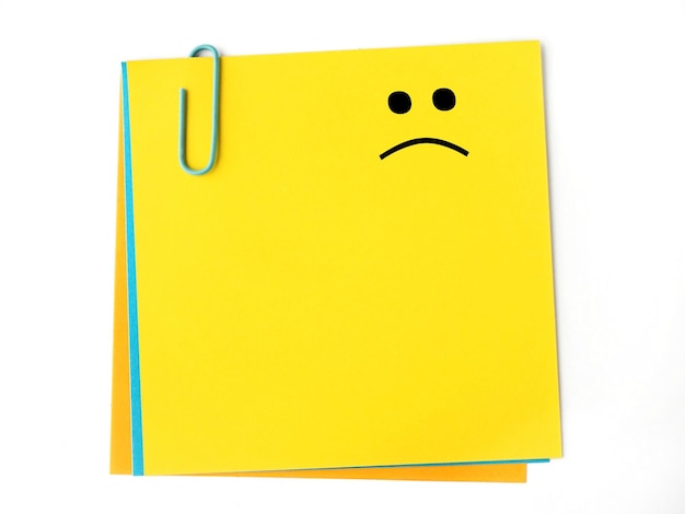 Photo a sad face on a blank yellow sticky note with copy space