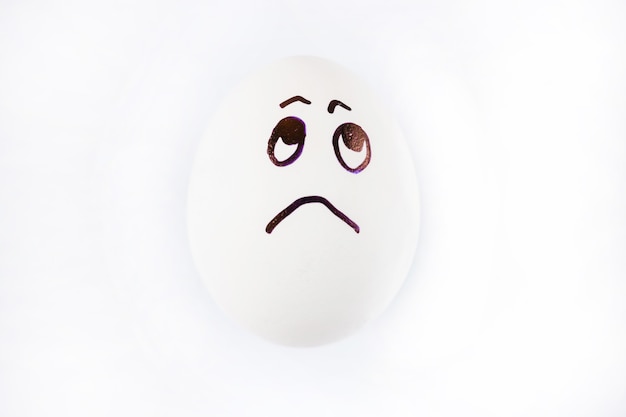 Sad face drawn on white Easter egg