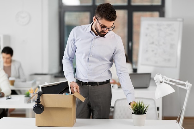 sad fired male office worker with personal stuff