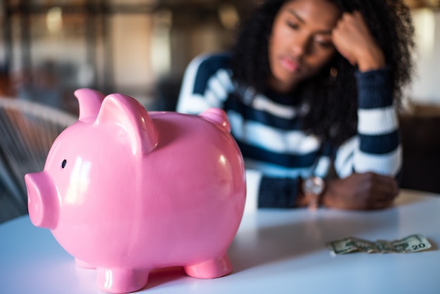 Sad frustrated black woman with piggy bank