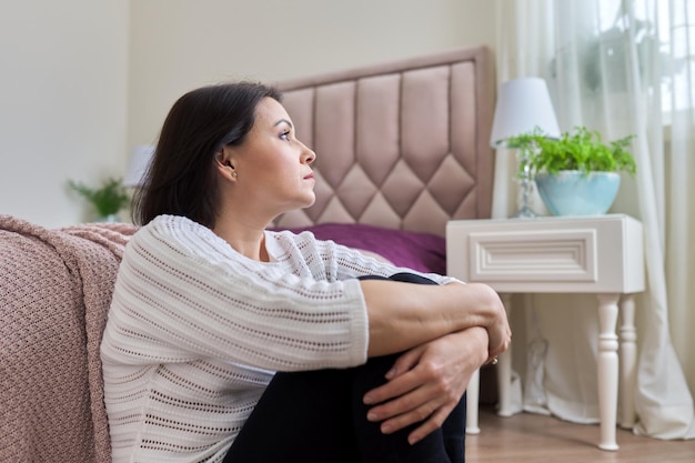 Sad frustrated depressed mature woman sitting at home on the floor