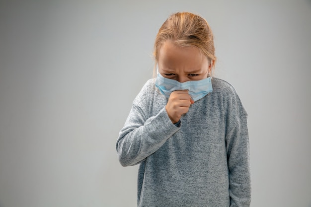 Photo sad future. caucasian little girl wearing the respiratory protection mask against air pollution and dust particles exceed the safety limits. healthcare, environmental, ecology concept.