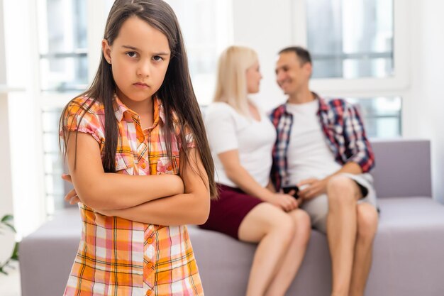 Грустная девушка слушает своих родителей, сидя дома на диване