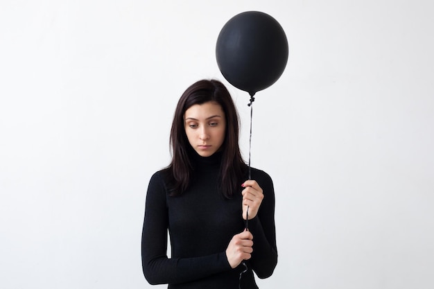 A sad girl holds a black balloon in her hands She is sad for the loneliness and devastation of the soul