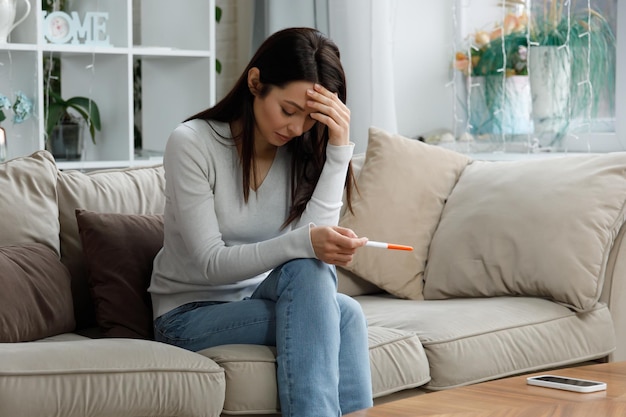 A sad girl holds a pregnancy test in her hand unwanted pregnancy concept