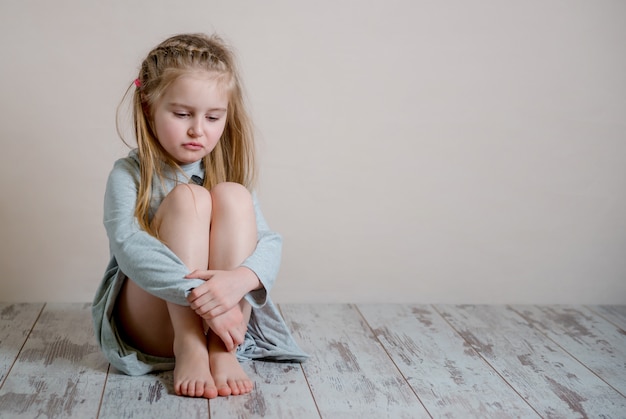 Ragazza triste che si siede da solo sul pavimento