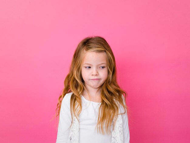 Sad girl standing against pink background