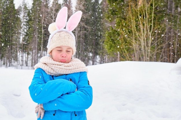 Sad girl teenager outdoors girl with carnival bunny ears on her head being sad because of snowy weather in spring