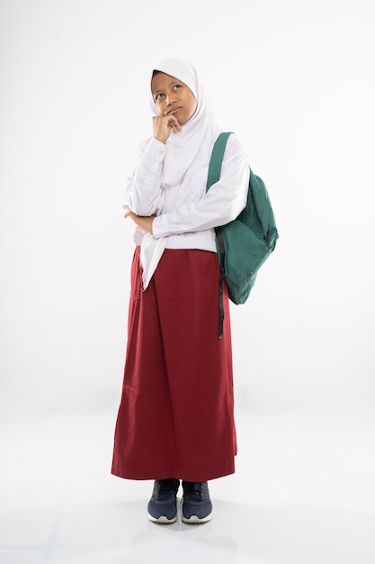 Грустная девушка в форме начальной школы с капюшоном стоит со школьной сумкой