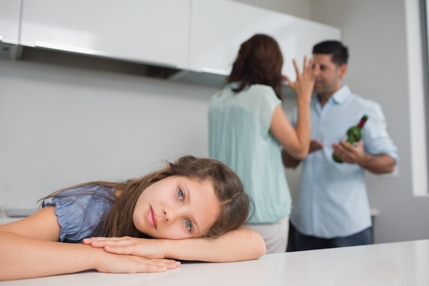 Sad girl while parents quarreling in kitchen