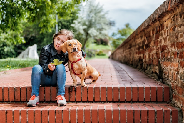 Sad girl with the dog sitting on the stairs