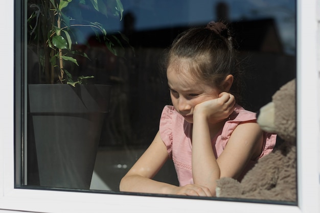 A sad girl with at the window. Quarantine, autoisolation.