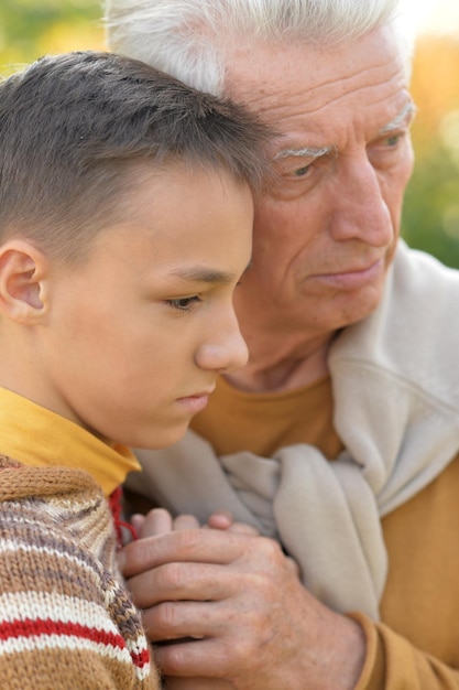 Sad grandfather and grandson hugging  in park