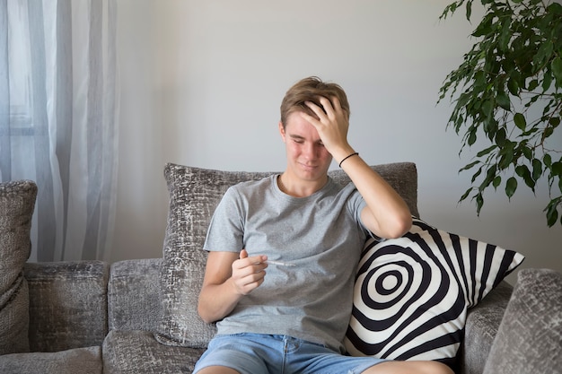 Sad guy is ill and looks at the thermometer. Medicine concept