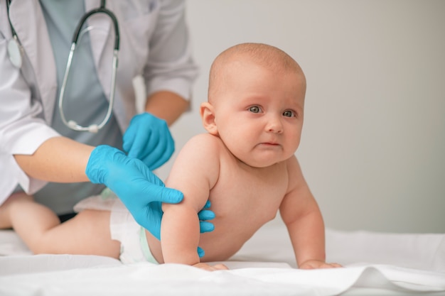 Sad ill pediatric patient lying on the couch during a medical exam