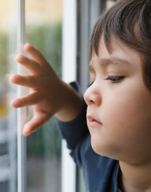 悲しい子供が窓から見える