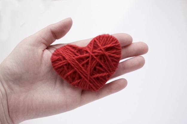 Sad knitted heart on the palm. The concept of separation of people, finished relationships, sadness