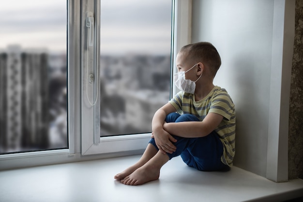 Photo sad little boy with protective mask during the isolation