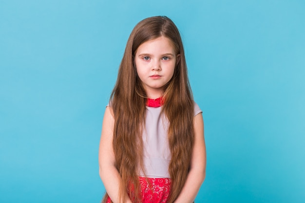 Sad little girl isolated on a blue background. childhood and children concept