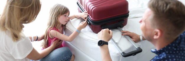 Sad little girl looks at suitcase sitting next to her parents