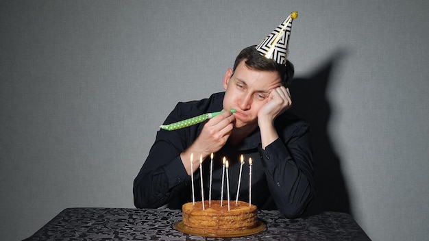 一人で誕生日、うつ病、危機を祝うパーティーハットの悲しい孤独な男。