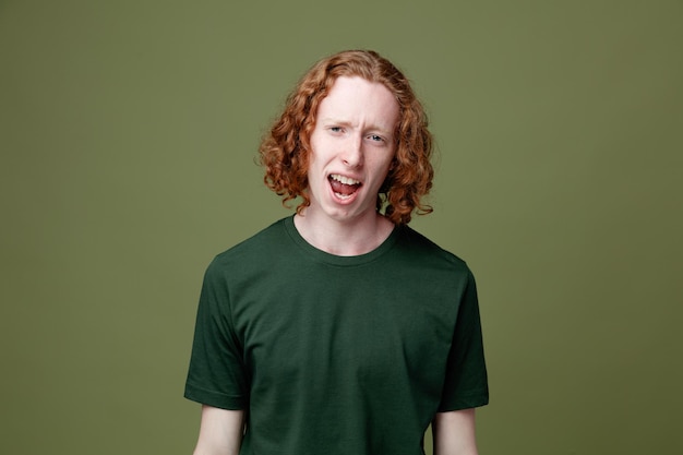 Sad looking at camera young handsome guy wearing green t shirt isolated on green background