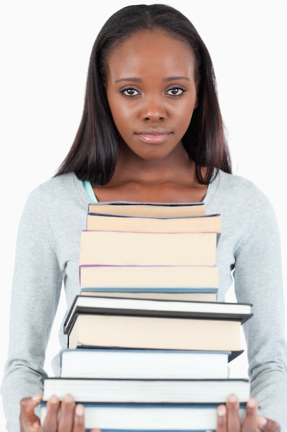 Sad looking young woman with pile of books