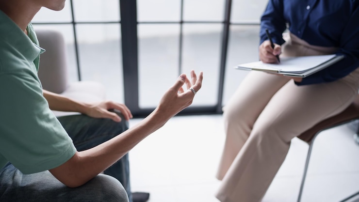 Photo sad male sitting on sofa patient discussing mental health issues with psychologist depressed asian man mental health treatment