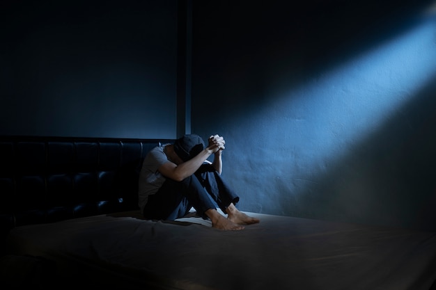 sad man on the bed in the darkroom