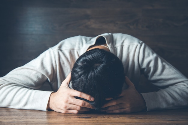 Sad man hand on head on dark background