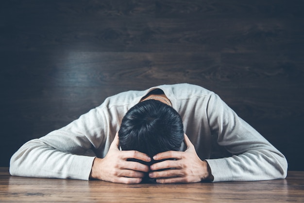 Sad man hand on head on dark background