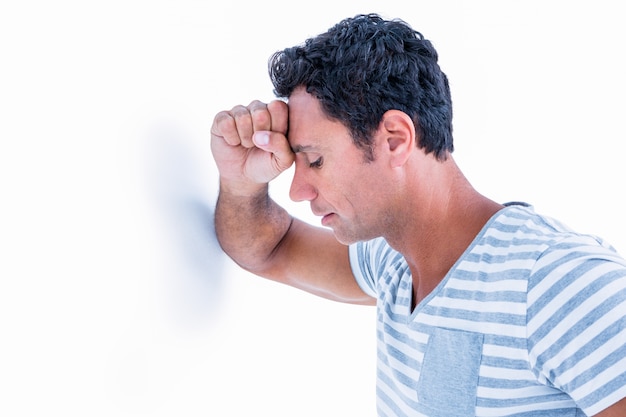 Sad man leaning his head against a wall