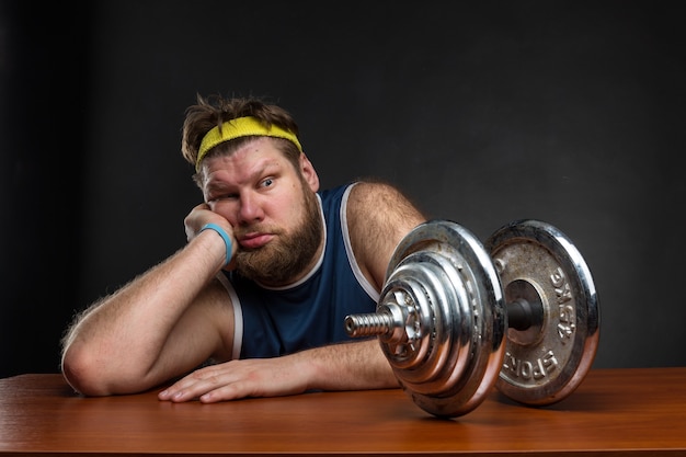 Sad man looking at a dumbbell at the table