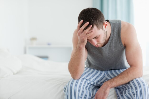 Sad man sitting on his bed