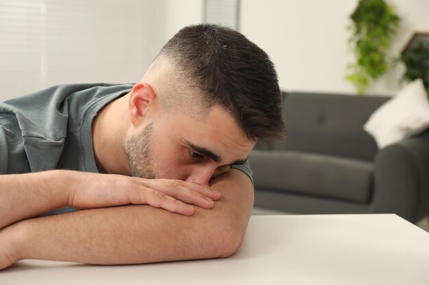 sad man at white table indoors space for text
