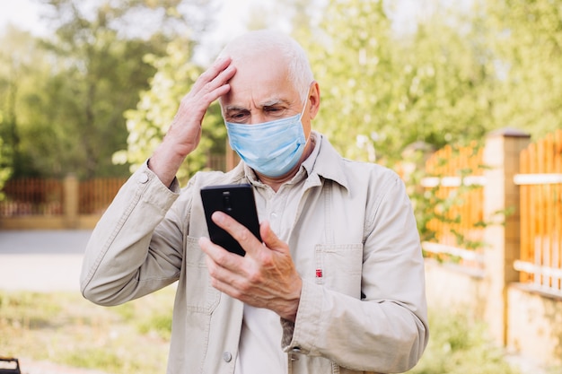 Sad man with medical face mask using the phone to search for news