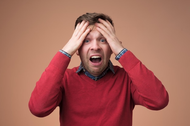 Sad mature man holding his head in hands and screaming