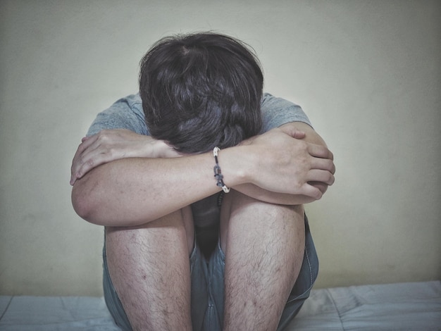 sad mid adult man sitting against wall at home