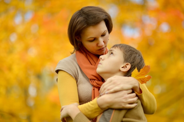 Sad mother with a son on a walk during the fall of the leaves in the park