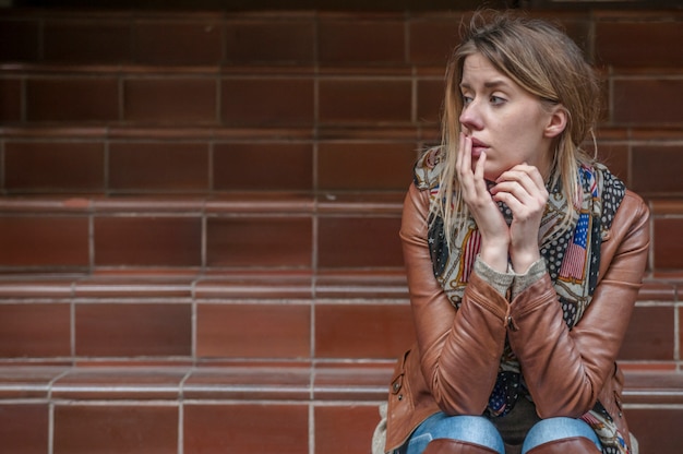 Sad news. Upset young woman with mobile phone reads the message.. Unhappy worried young woman talking on phone. Sitting sad and alone