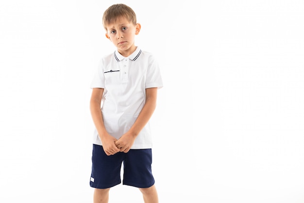 Грустный обиженный мальчик с челкой в белой футболке на белом с копией пространства