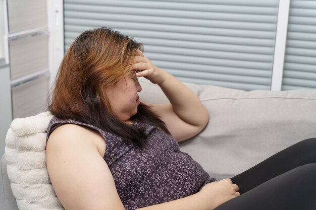 Sad Overweight plus size woman thinking about problems on sofa upset girl feeling lonely and sad from bad relationship or Depressed woman disorder mental health